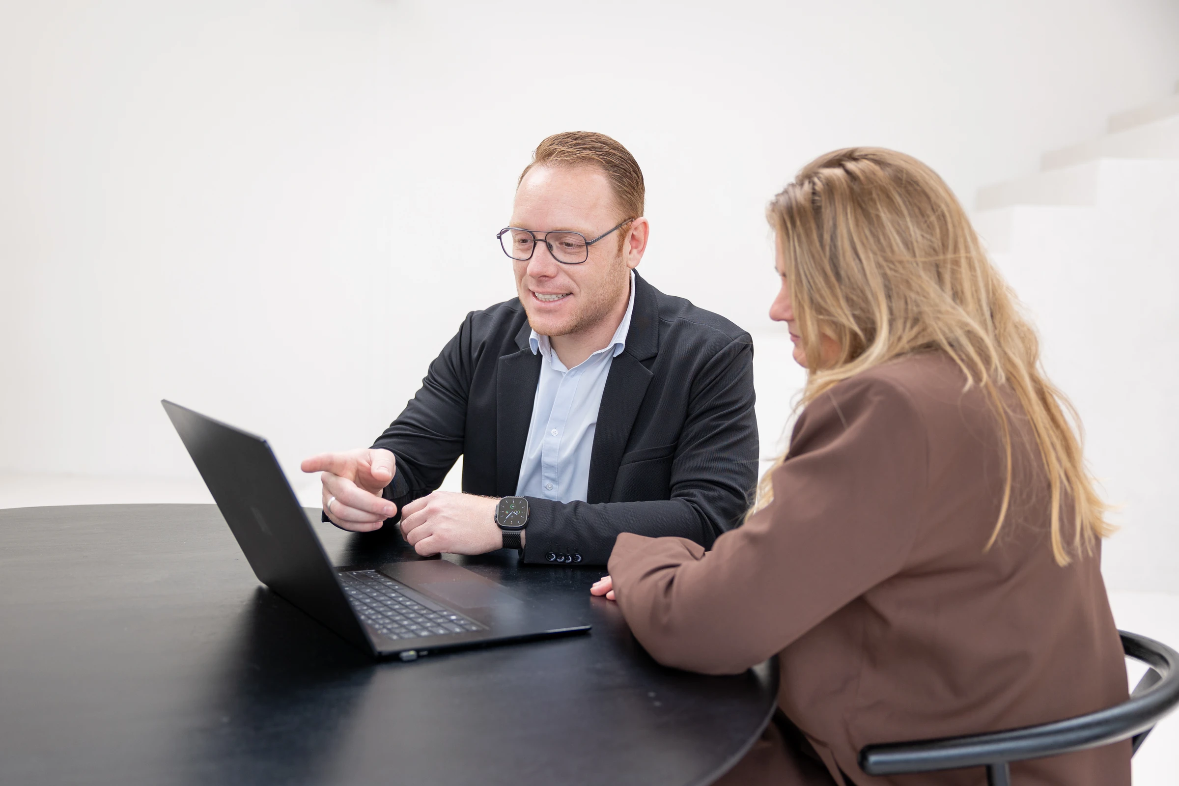 Thomas wijst iets aan op zijn laptop terwijl een klant meekijkt